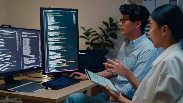 Engineers reviewing code together on multiple screens